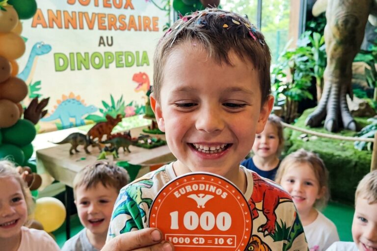 Enfant qui fête son anniversaire à Dinopedia avec une pièce de 1000 EuroDinos